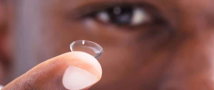 man holding contact lens on finger