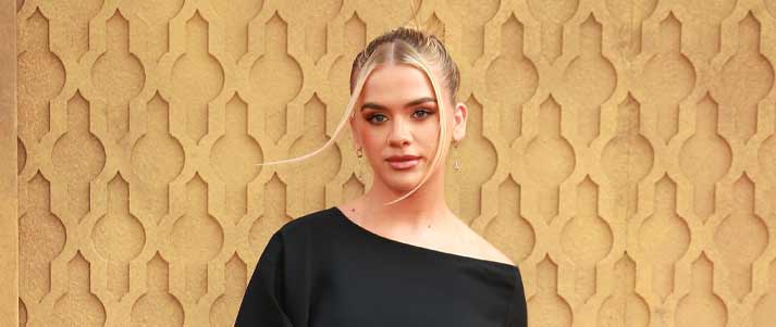 Grace Beverly standing in front of a gold geometric background