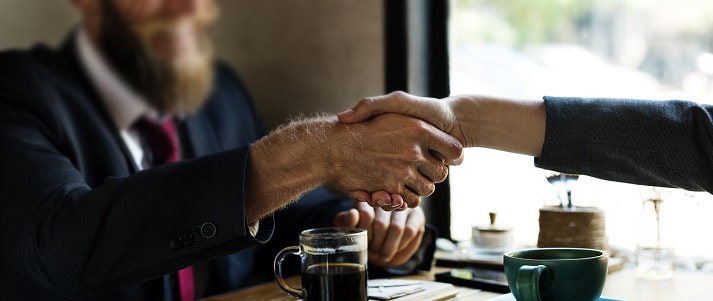 two professionals shaking hands over a table