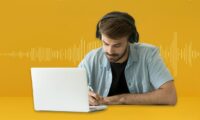 Man transcribing at desk with laptop and sound wave background