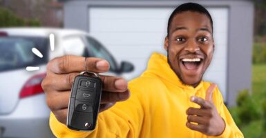 man holding car key in front of car in driveway