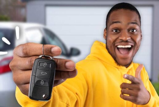 man holding car key in front of car in driveway
