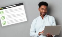 man using laptop next to job application form