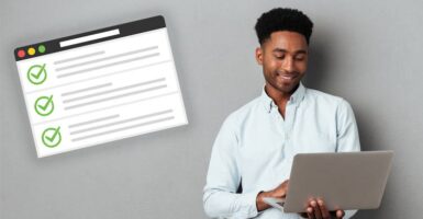 man using laptop next to job application form