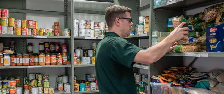 volunteer taking food off food bank shelf