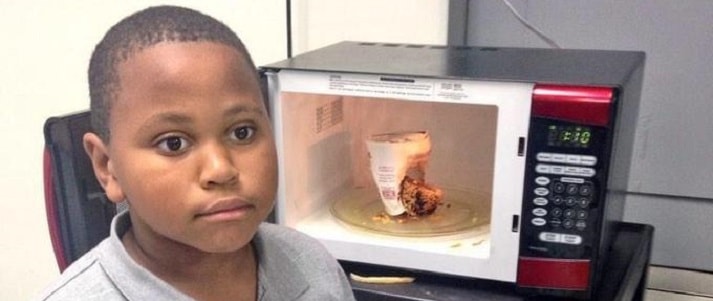 child standing in front of dirty microwave