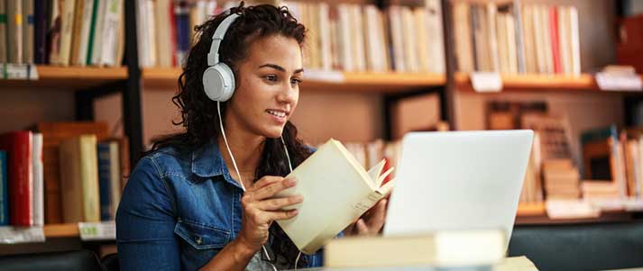 Woman in library studying with laptop books