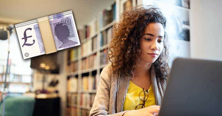 young woman sat using laptop next to money