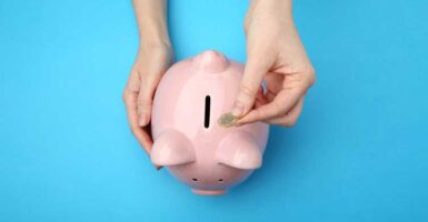 Hand putting pound coin into piggy bank