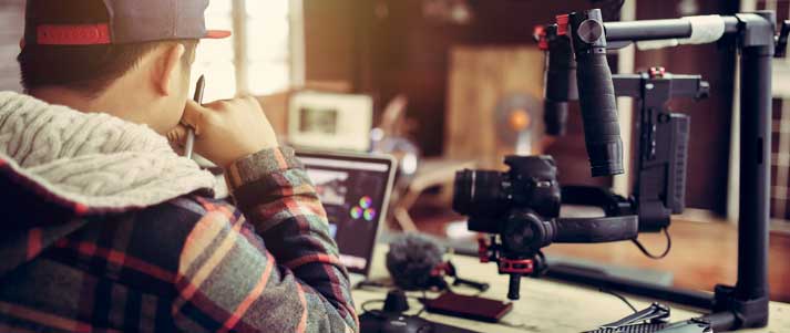 man at desk with film equipment and laptop