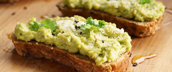 Avocado toast with oil herbs salt guacamole on wooden board