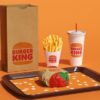burger king burger on tray with fries cups with straws paper bag orange background