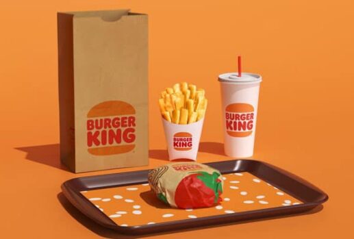 burger king burger on tray with fries cups with straws paper bag orange background
