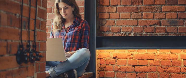 Woman working on a laptop with exposed brick