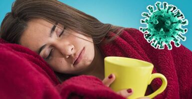 Woman in blanket with mug and coronavirus germ