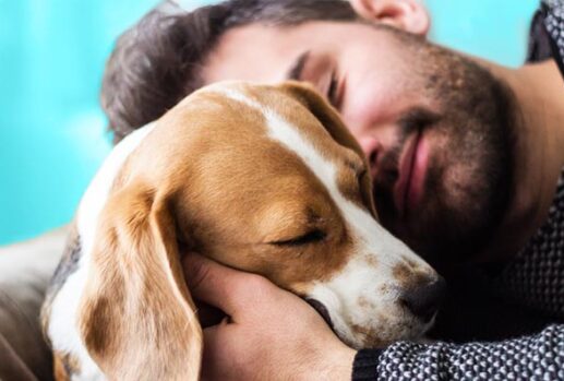 man cuddling dog looking happy