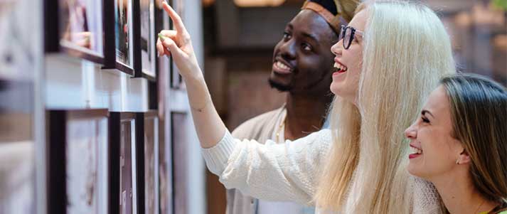 Three people looking at photos in exhibition