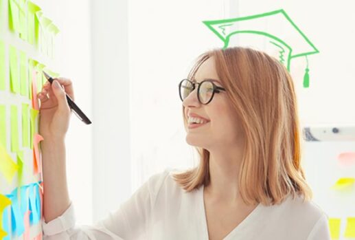 Woman writing on post it notes with drawn graduate cap