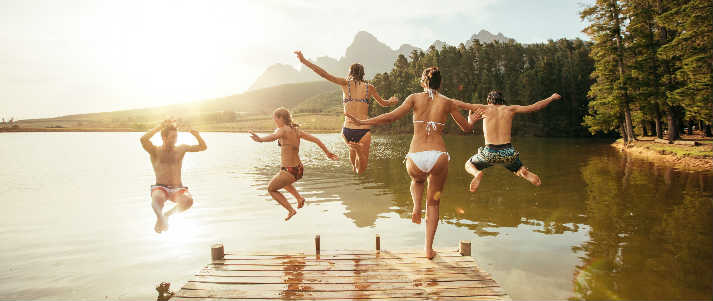 group of friends jumping in lake