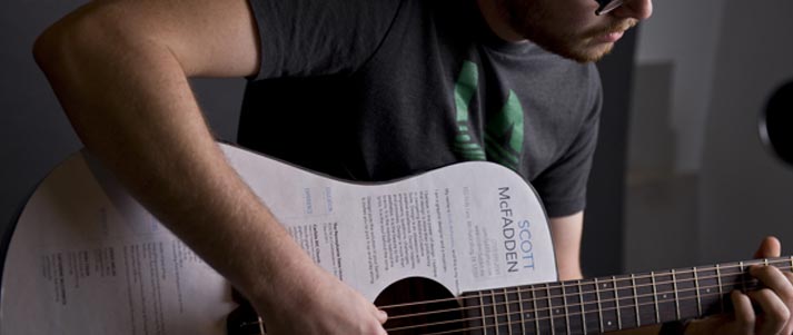 man playing guitar with CV written on it