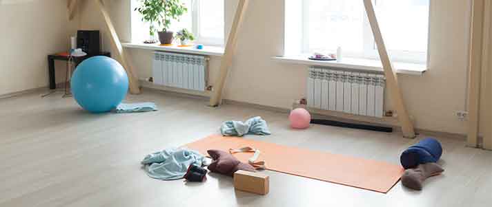 home gym with pillows and weights in light room wooden floor beams