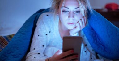 Woman in bed looking at phone