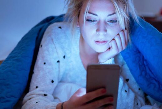 Woman in bed looking at phone