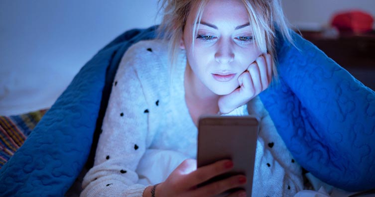 Woman in bed looking at phone
