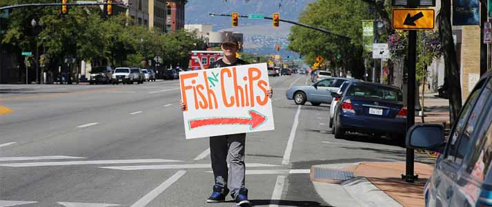 man holding fish and chips sign