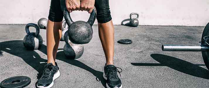 woman holding a weight and bending knees squatting down in gym