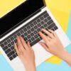 Hands on laptop keyboard with blue and yellow background