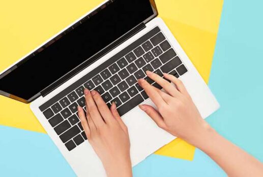 Hands on laptop keyboard with blue and yellow background
