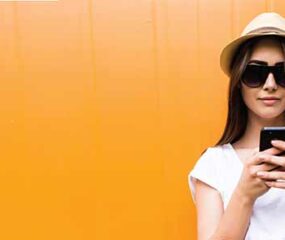 girl in hat holding scrolling phone