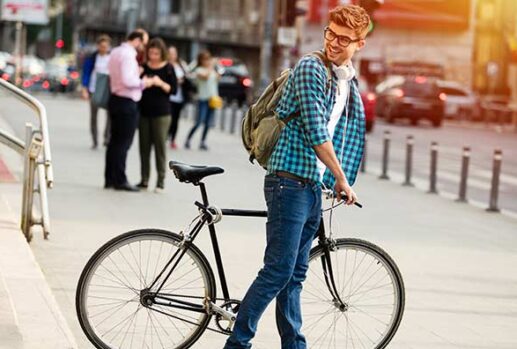 man standing in front of steps with bike looking back with headphones and backpack on