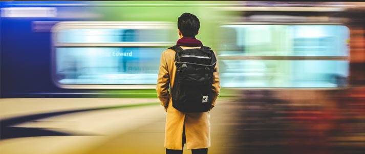 man with a backpack with train in the background