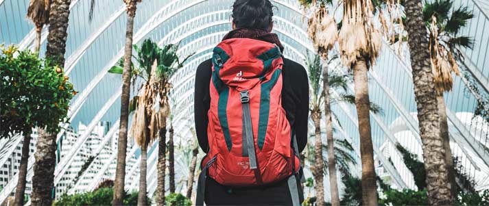 woman with backpack in front of palm trees