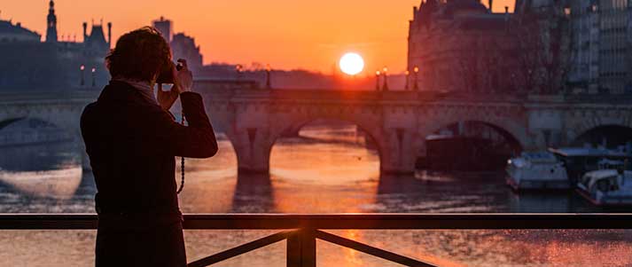 man taking photo of paris at sunset