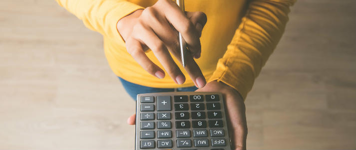 person using calculator holding pen