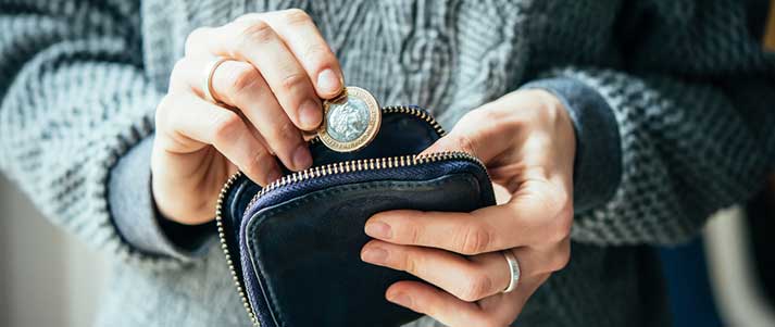 woman putting pound coin into purse