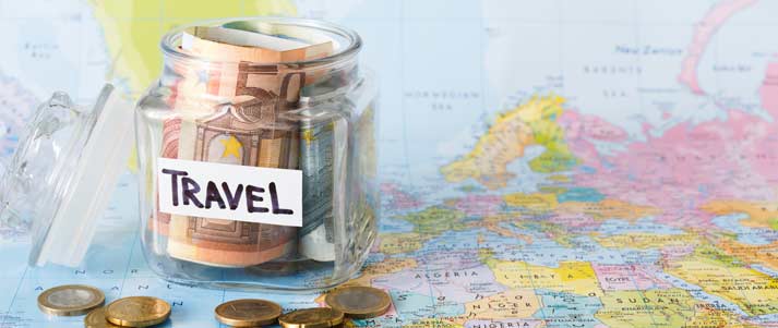 money in a transparent pot with the word 'travel' on a map