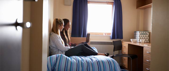 two female students sat on bed