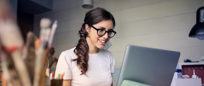 woman wearing glasses working on a laptop