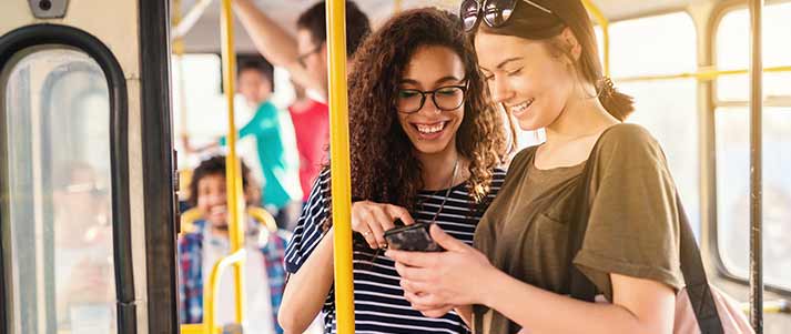 Two friends on a bus looking at phone