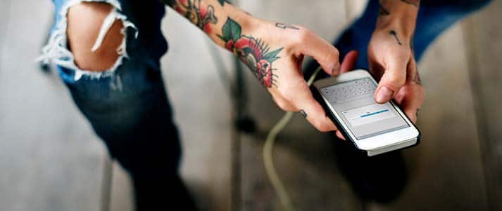 man with tattoos using phone
