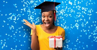 Woman with graduation cap holding present