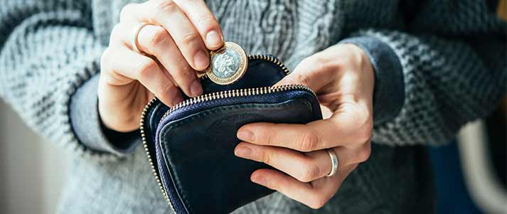 woman holding a pound coin and putting it in the wallet