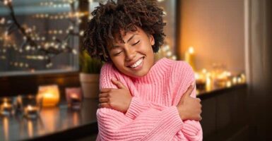 Woman hugging herself with candles in the background