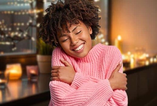 Woman hugging herself with candles in the background