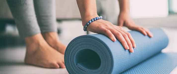 blue yoga mat being rolled up by woman