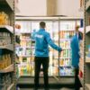 man stacks shelf in zapp blue jumper groceries